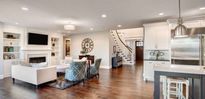 Luxurious deep espresso hardwood flooring unifying a transitional living room (white sofa, patterned armchairs, fireplace) and adjacent kitchen (white cabinets, stainless steel, island seating)—showcasing seamless flow and contrast.