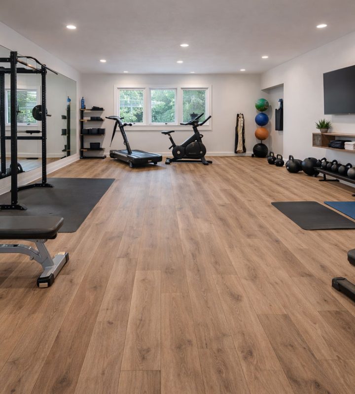 Spacious finished basement with light wood-grain LVP flooring, featuring a media lounge (sofa, TV, shiplap wall), pool table, and custom bar with stools—demonstrating durability and style for high-use spaces.
