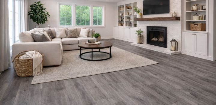 Sleek gray wood-look LVP flooring anchoring a calm, modern living space with ivory sectional, neutral rug, white brick fireplace, floating shelves, and abundant natural light—perfect for high-traffic, pet- and kid-friendly homes.